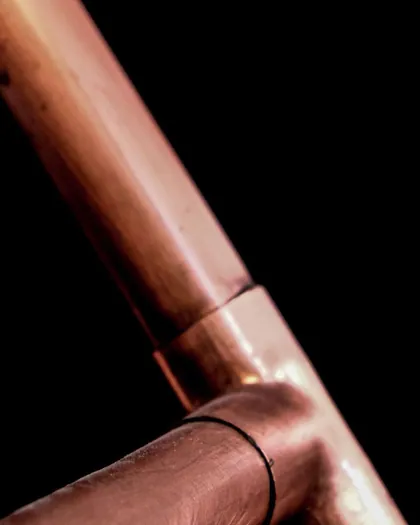 Ends of copper pipes against a dark background
