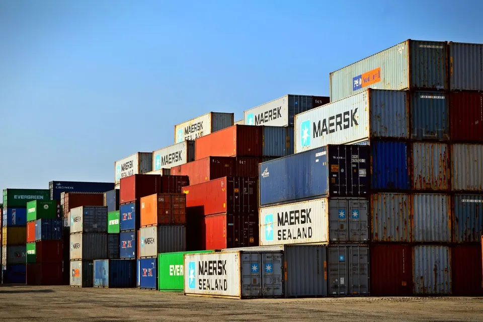 Shipping containers stacked at a port under a clear sky