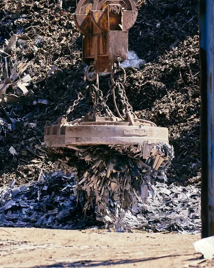 Crane lifting scrap metal in an industrial yard